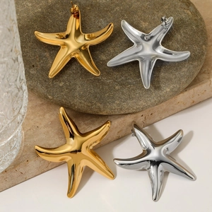 Polished gold and silver starfish earrings displayed on natural stone pedestals