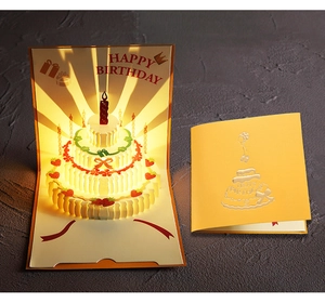 Close-up of 3D pop-up birthday card with warm light glowing through paper cake