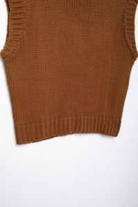 Detail view of caramel knit sweater vest featuring thick ribbed texture and hemline finish