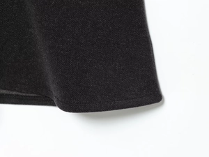 Close-up of black twill fabric texture and fine lockstitch hem on a slim dress