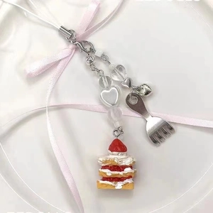 Handmade strawberry cake keychain with metal fork charm and white heart beads on plate