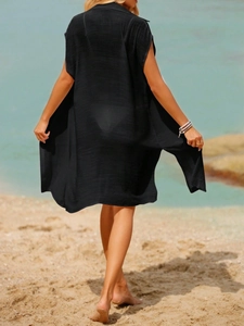 Sheer black sleeveless beach cover-up with high slits shown from a back view on a beach