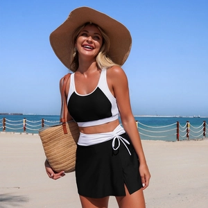 Two-piece color block swimsuit with black swim skirt and drawstring at a sunny beach