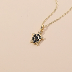 Detail of a gold turtle pendant with black enamel shell and clear crystal embellishments