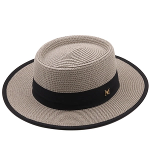 Détail d'un chapeau de paille beige avec ruban noir et logo M doré pour femme élégante