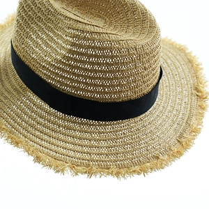 Macro detail of hand-woven straw hat with black ribbon and unique frayed edge design