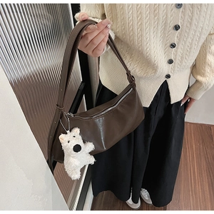 Brown PU leather shoulder bag worn by model featuring a white plush bear pendant