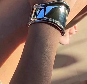 Gros plan sur un large bracelet jonc argenté poli avec finition miroir sur un mannequin