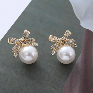 Détail macro de boucles d'oreilles papillon dorées avec zircon et perles blanches élégantes