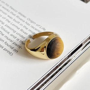 Close-up of golden S925 silver ring with round tiger eye stone on a magazine background
