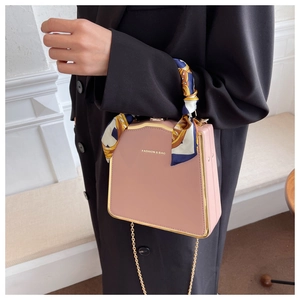 Detail of pink box bag with gold metal trim and silk scarf wrapped around handle