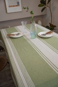 Close-up of green and beige striped cotton linen tablecloth on a dining table