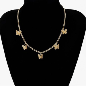 Elegante collana girocollo a farfalla dorata con cinque ciondoli su un busto per gioielli