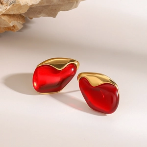 Irregular red resin heart earrings with gold trim on minimalist stone backdrop