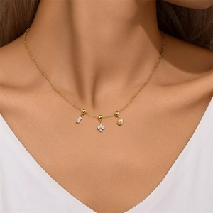 Close-up of gold necklace with rectangular zircon, clover zircon, and pearl charms