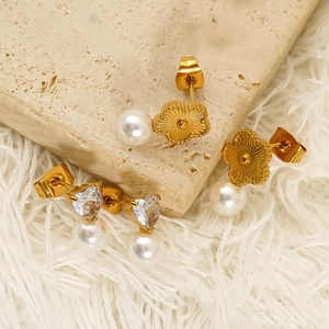 Elegant gold flower and heart studs with hanging pearls on stone display base