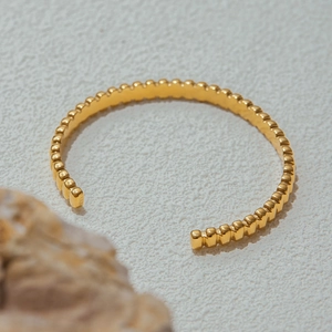 Close-up of golden beaded stainless steel cuff bracelet with high polished finish
