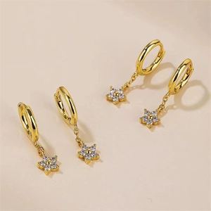 Vue détaillée des boucles d'oreilles fleur en or avec zircons blancs sur fond beige