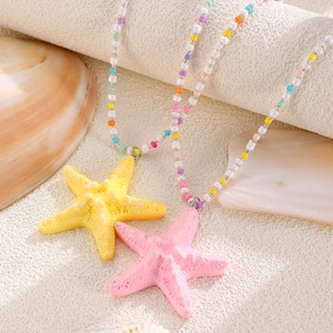 Detail of bohemian summer beach necklaces with yellow and pink starfish on colored beads