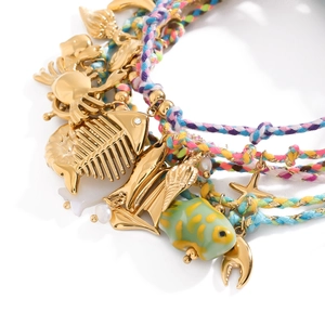 Macro shot of colorful woven ocean bracelets with gold charms like shells and starfish