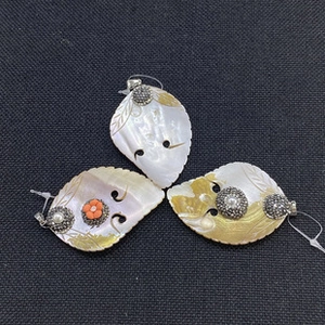 Macro detail of leaf-shaped natural sea shell pendants with gold inlay and pearl accents