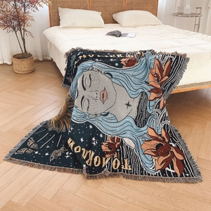 Bohemian style blue woven blanket with tassels and sun pattern on a white bed