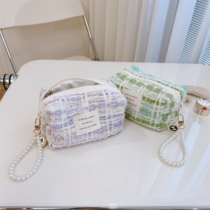 Macro detail of elegant tweed pouches with pearl handles and decorative metal charms