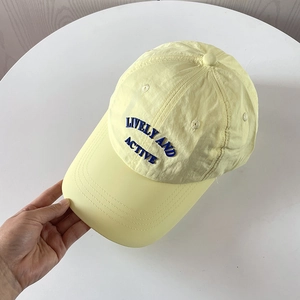 Close-up detail of blue embroidered Lively and Active text on a yellow nylon baseball cap