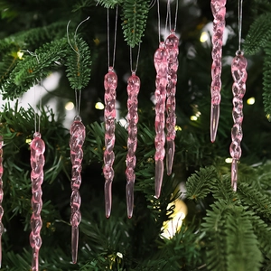 Close-up of pink spiral icicle ornament hanging on a Christmas tree with warm bokeh
