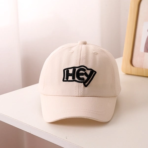 Close-up of HEY letter embroidery on a beige kids' baseball cap with cotton texture
