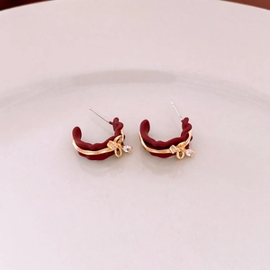 Detail of burgundy C-shaped earrings with gold bow accents and clear rhinestones