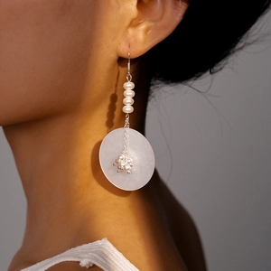 Gros plan de longues boucles d'oreilles élégantes en perles et résine sur un mannequin