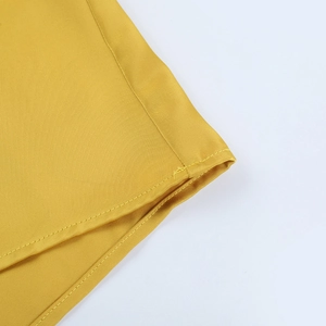 Gros plan sur la robe en satin jaune montrant les coutures doubles et la texture