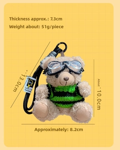 Detail view of plush bear keychain in green sweater with goggles and size measurements