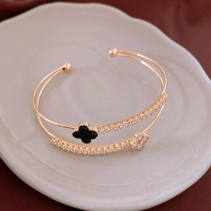 Detail of double-layer gold bangle with black clover and sparkling zircon accents