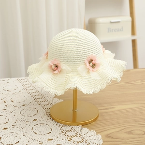 Détail d'un chapeau de paille pour enfant avec nœud en maille rose et décor floral