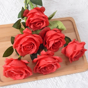Detail view of artificial red roses with velvet texture on a wooden tray for home decor