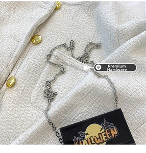 Detail of Halloween crossbody bag with silver chain on white tweed jacket with gold button