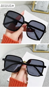 Detail view of large square black sunglasses with dark grey lenses and rivet accents