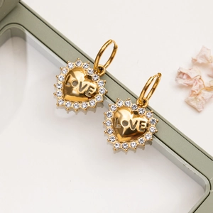 Detail of 18K gold heart earrings with LOVE engraving and white crystals on a jewelry box