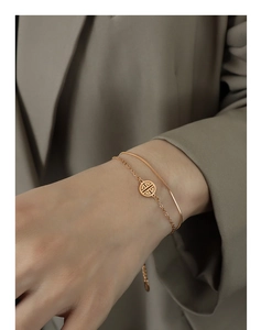 Detail of 18k gold layered snake chain bracelet with round hollow pendant on wrist