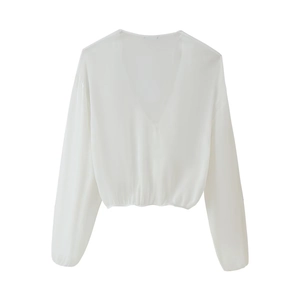 Detailed view of women's white V-neck long-sleeve blouse with elegant layered fabric textures