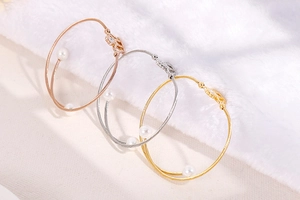 Close-up of steel cable bracelets with pearls in rose gold, silver and gold finish