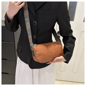 Brown leather texture pillow bag with patterned wide strap shown on model's shoulder