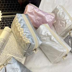 Detailed close-up of quilted heart pattern cosmetic bags in silver, pink, and white colors