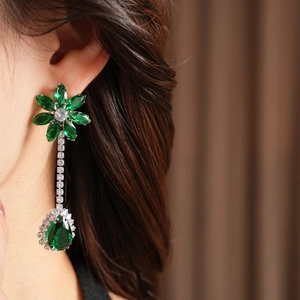 Close-up of elegant green floral drop earring with sparkling zircon crystals on model