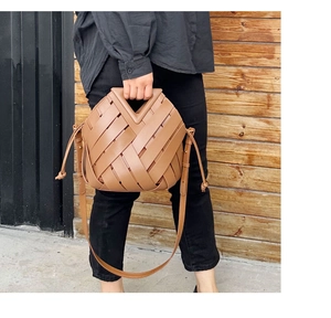 Close-up of woven brown leather handbag with triangular magnetic buckle detail