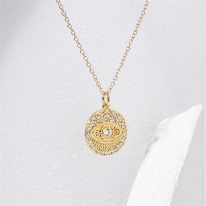 Detail of gold evil eye pendant necklace with micro-paved zircons on a white rock base
