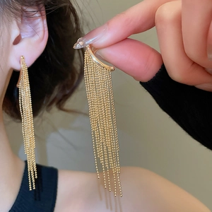 Detailed close-up of long gold ball chain tassel earrings with smooth curved hooks