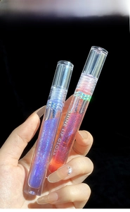 Macro shot of two high-shine glitter lip glosses in purple and coral on black background